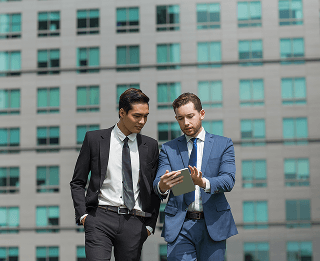 two-content-business-men-using-tablet-walking